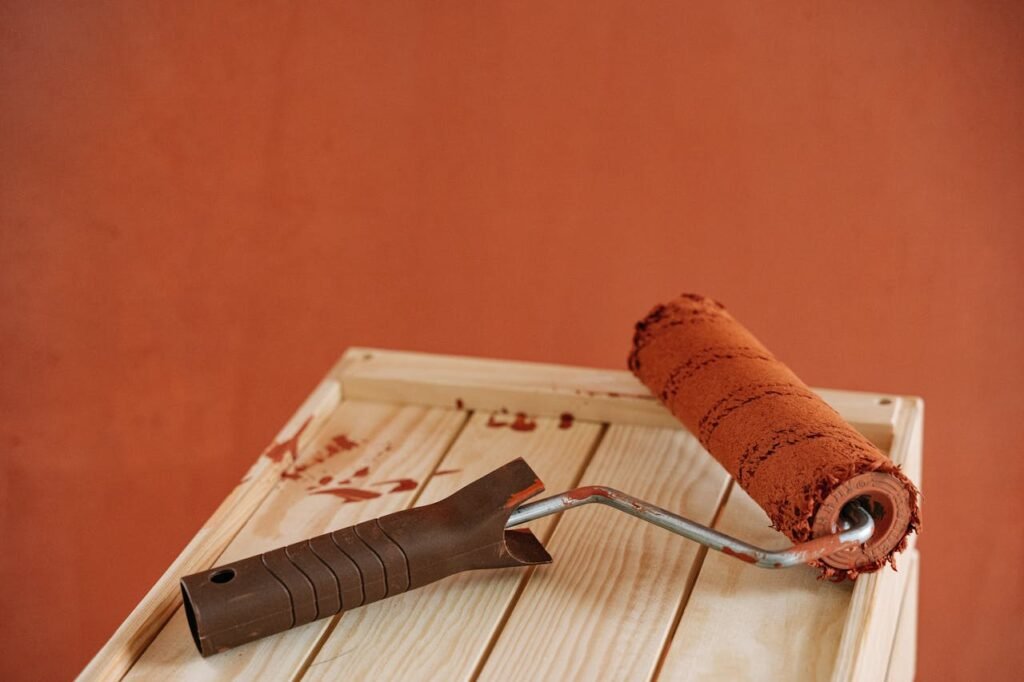 pexels-photo-5799375 A paint roller with rustic brown paint on a wooden surface against an earthy wall.